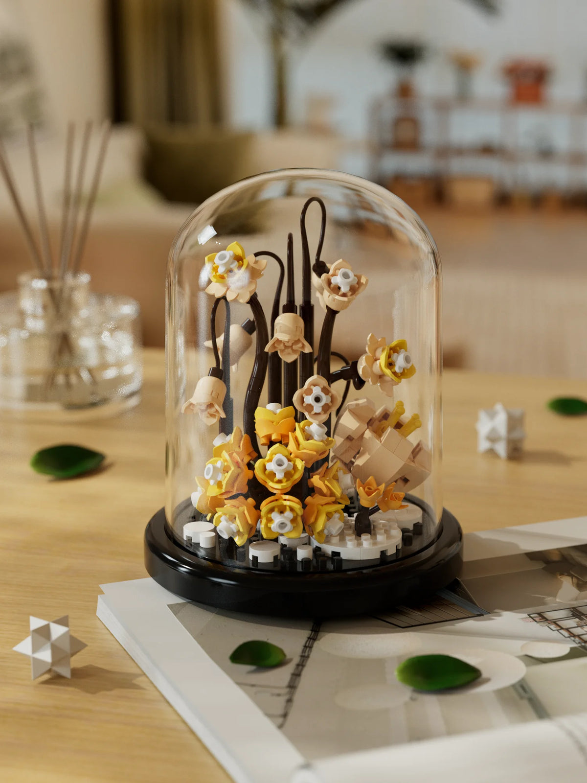 A glass dome display of a buildable eternal rose flower kit featuring small yellow and white flowers on a black base.