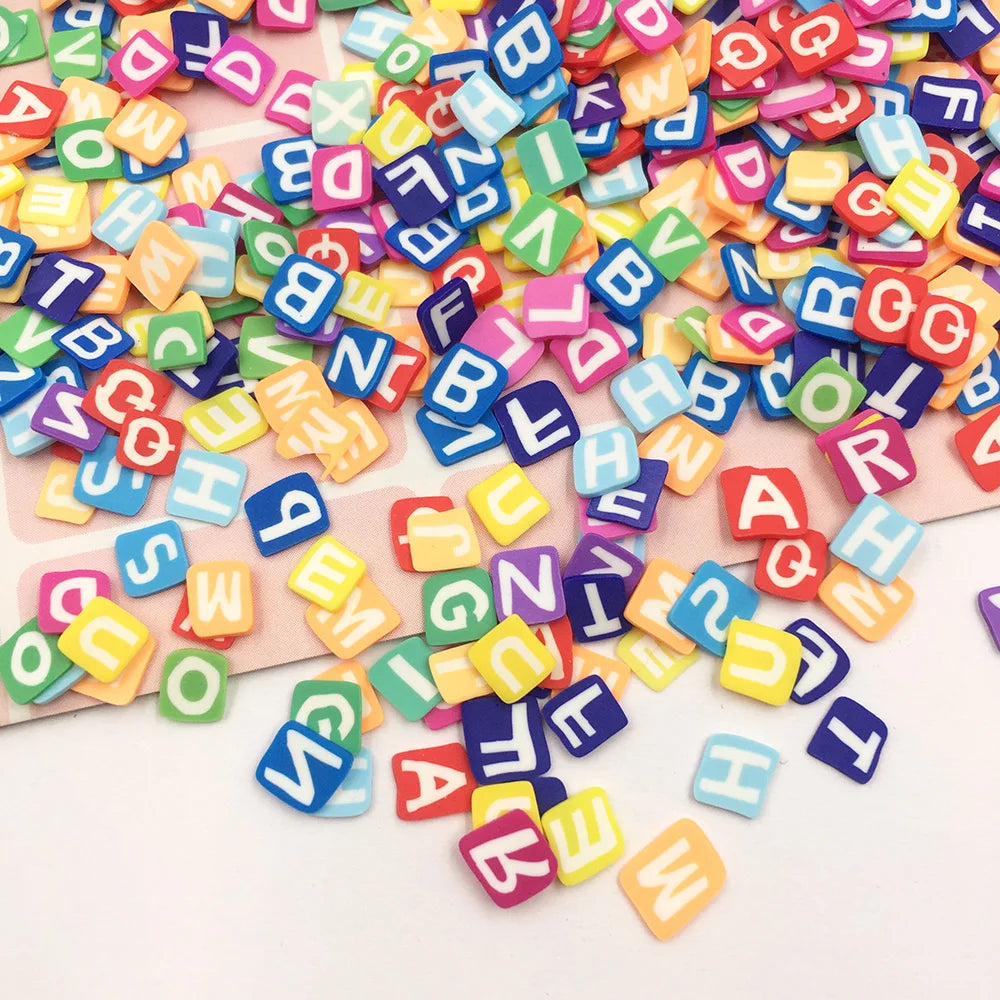 A colorful mix of polymer clay letter sprinkles in various shapes and colors scattered on a white surface.