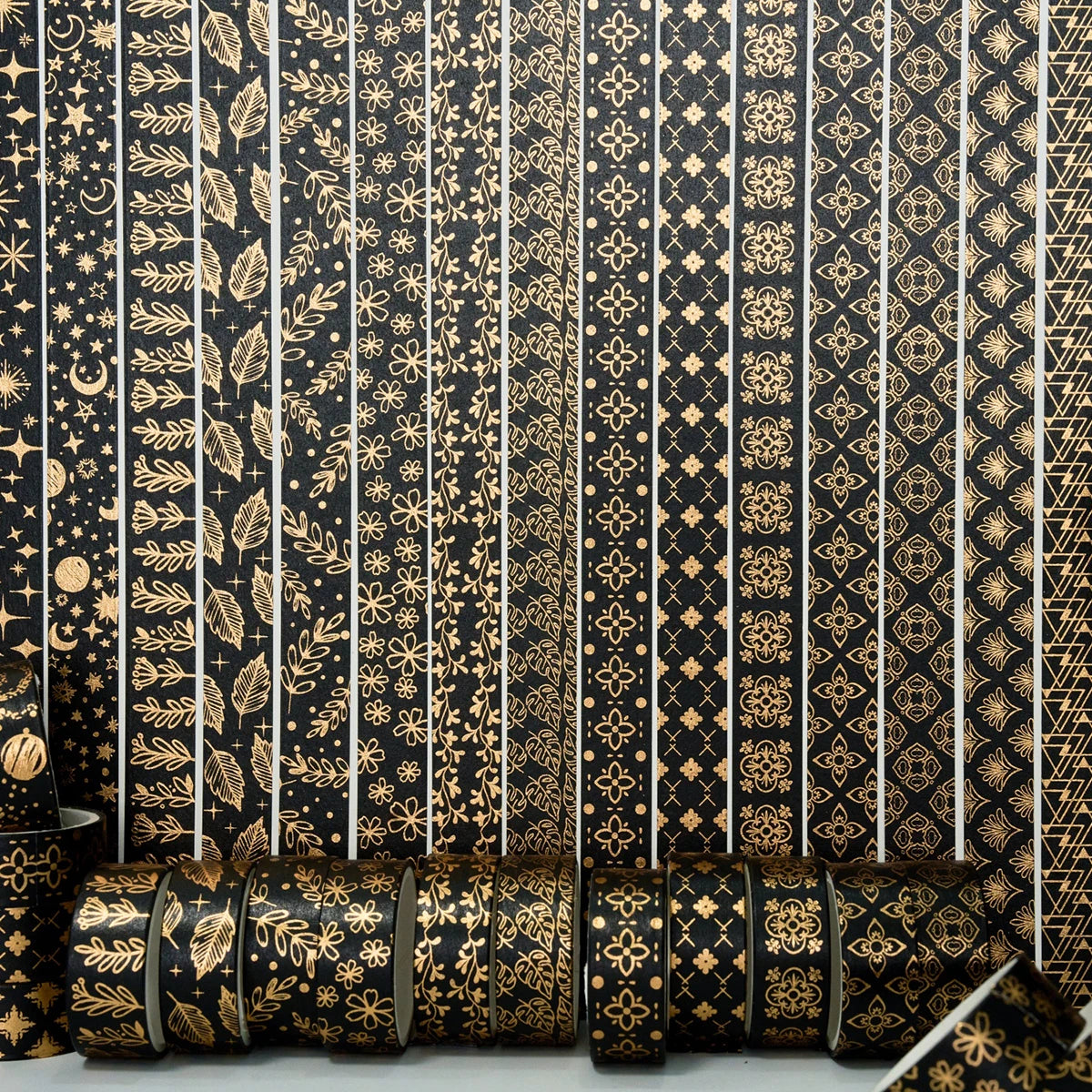 Rolls of black and gold foil washi tape set featuring intricate floral and geometric patterns