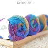 A bundle of hand-dyed rainbow merino wool yarn in various shades of blue, purple, and green.