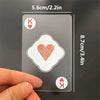 A hand holds a transparent playing card with a King of Hearts symbol, showing its size and detail.