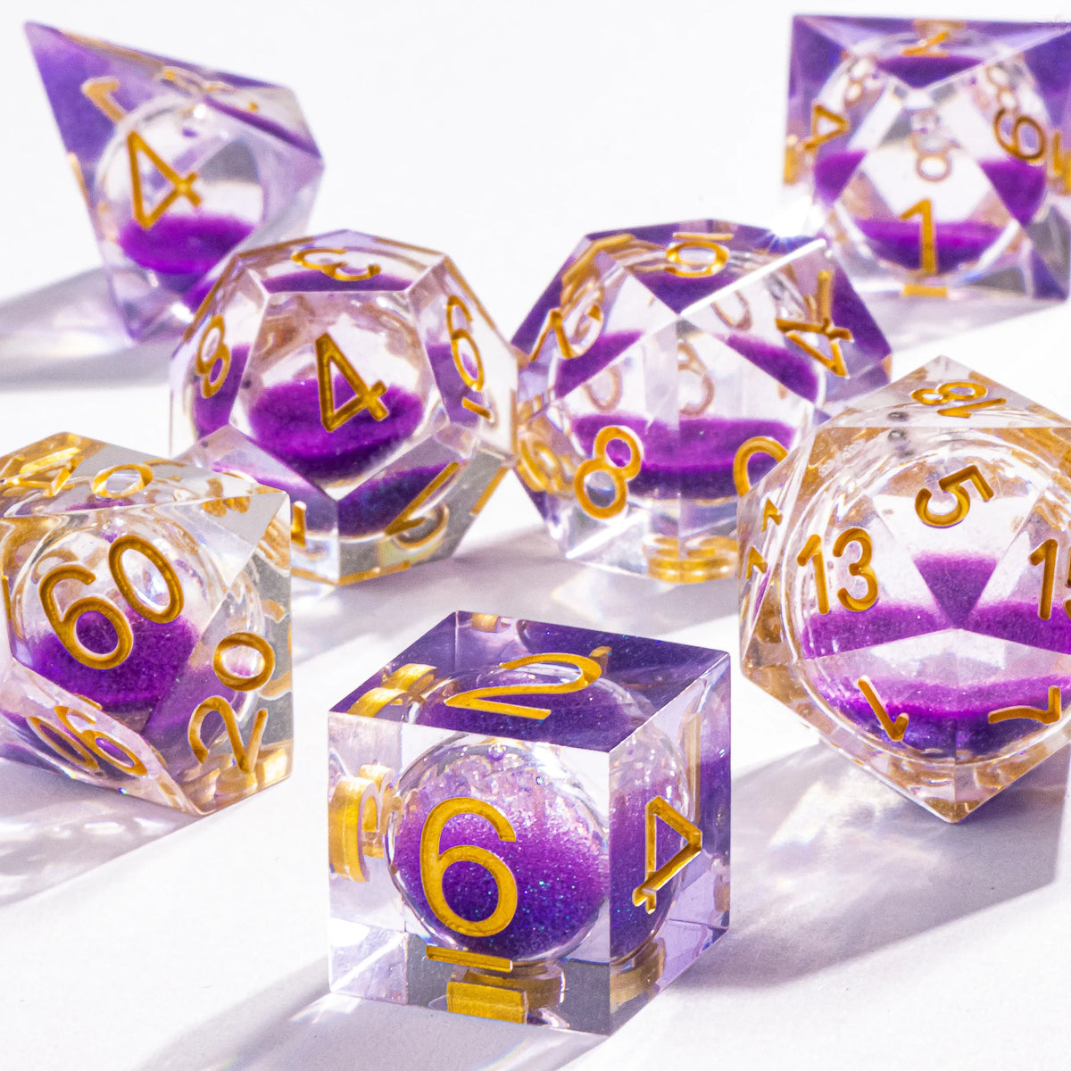 A set of handmade liquid core polyhedral dice with a galaxy finish, showing various colored dice on a white surface.