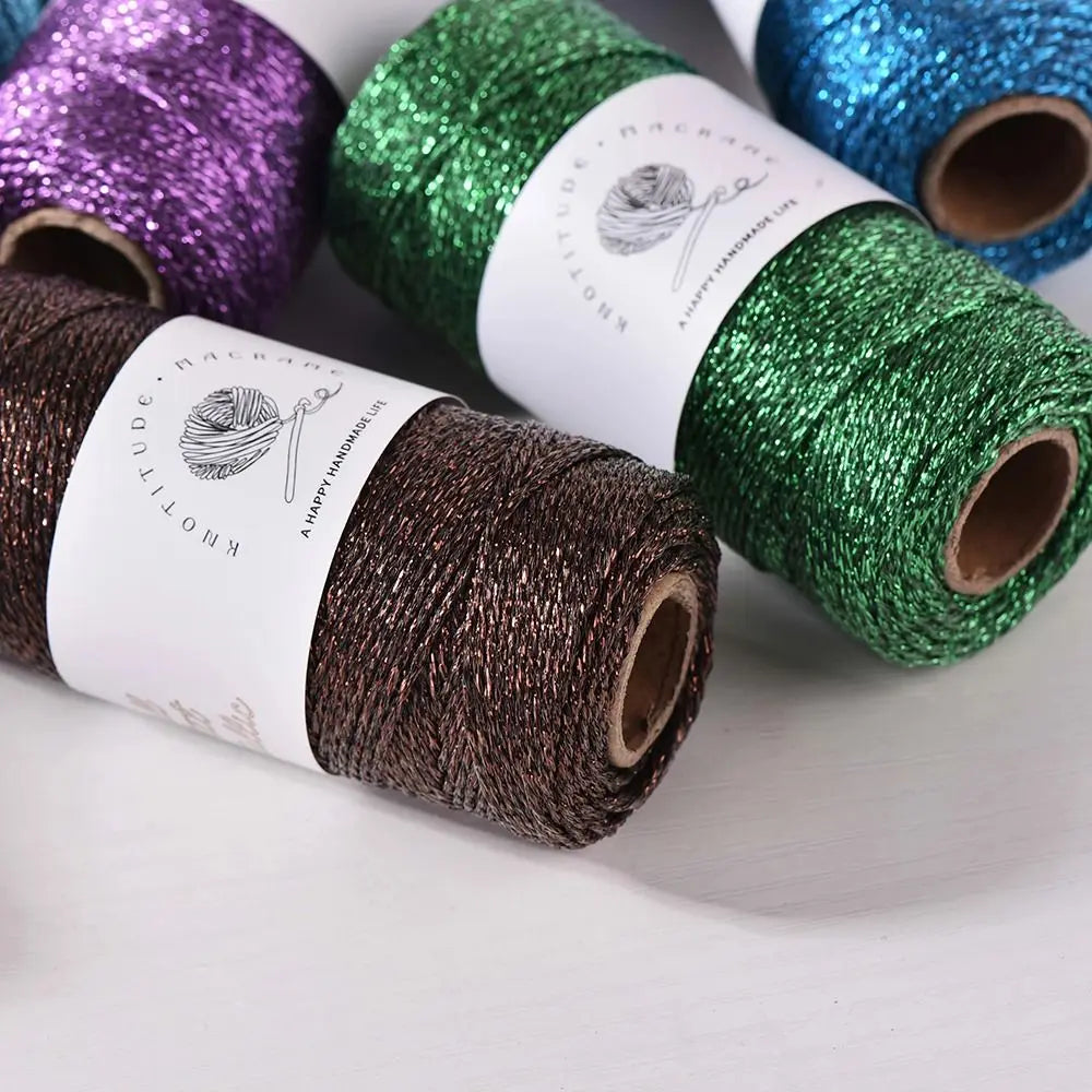 Rolls of metallic glitter yarn in purple, green, and blue for knitting and crochet projects
