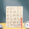 A wooden Montessori letter tracing board showing the alphabet from A to Z carved into the wood.
