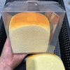 A clear plastic package containing a squishy toy shaped like a loaf of bread with an orange and yellow gradient color.