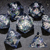 A collection of polyhedral dice, including d4, d6, d8, d10, d12, and d20, with a galaxy finish, scattered on a dark surface.