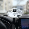 A silver clip-on car vent drum cymbal with an adjustable hook resting on a black car interior.