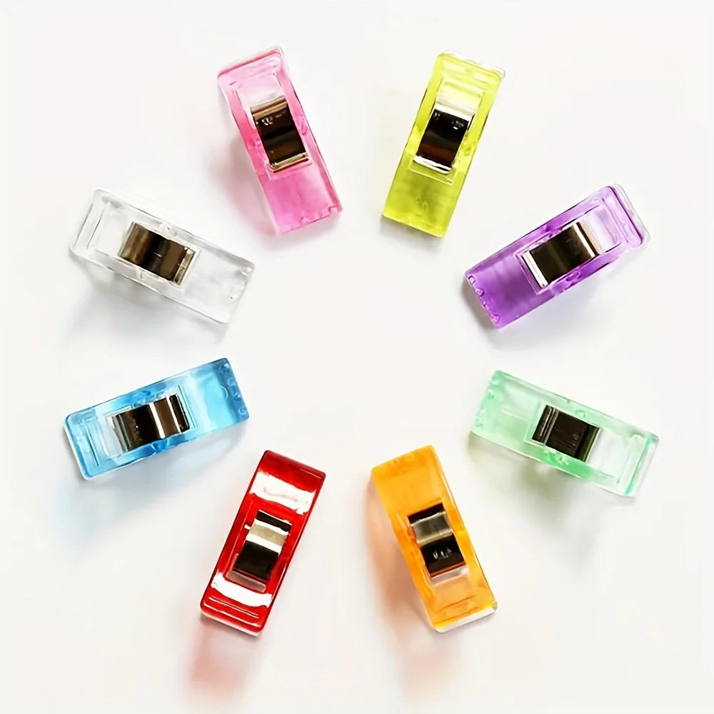 An eight-piece set of diamond painting clips in various translucent colors including pink, yellow, purple, and green.