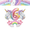 Pink and purple foil balloons shaped like the number 6 and a rainbow arch for a unicorn party