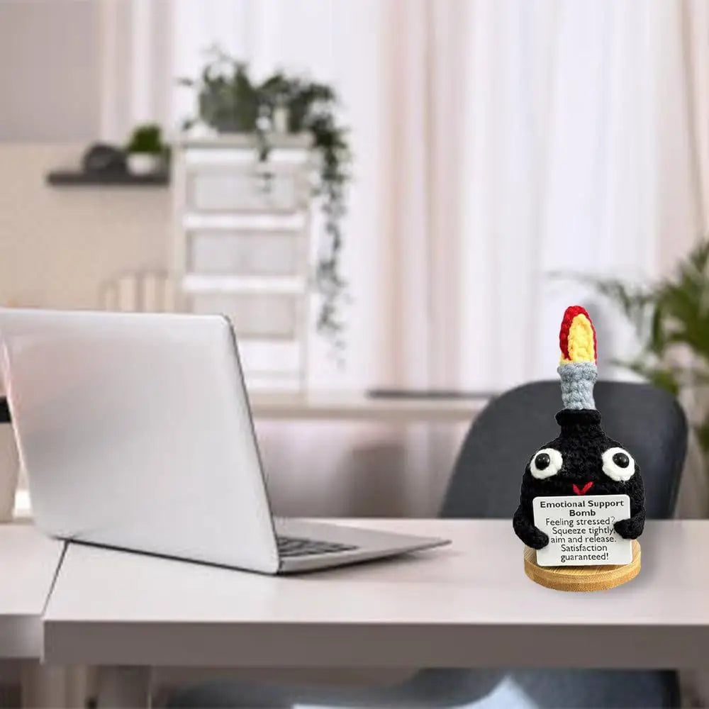Handmade crochet F-bomb doll with an encouragement card sitting on a white desk.