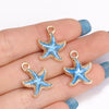 Gold-toned starfish enamel charms on a hand