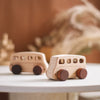 A wooden Montessori push cart toy featuring a handcrafted beech car and bus set on a white surface.