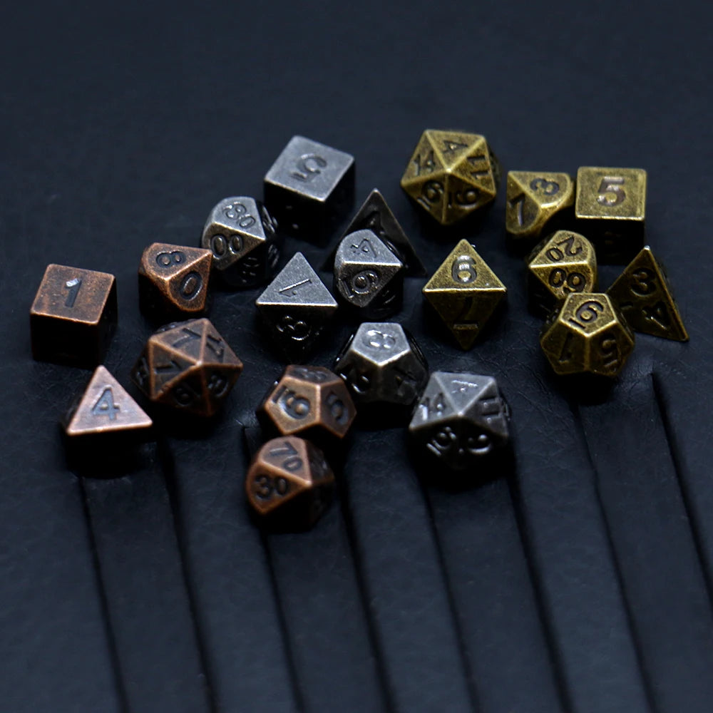 A collection of seven antique metal polyhedral dice showing various numbers and shapes on a dark surface.