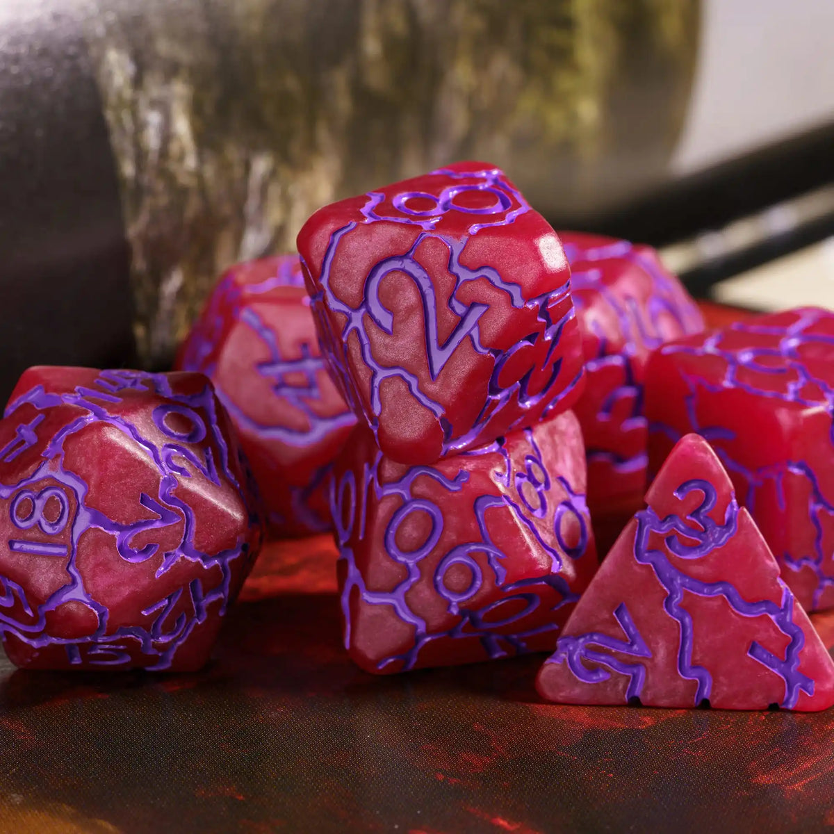 A set of seven frosted red resin polyhedral dice resting on a dark surface.