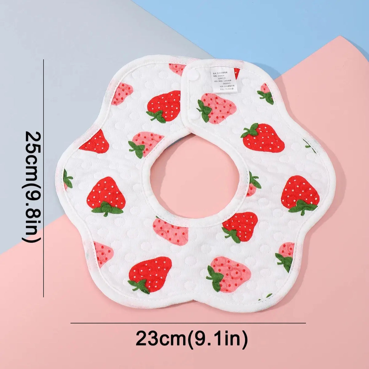 A white baby bib with red strawberry patterns is shown against a light background.