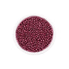A clear container filled with small, round, deep magenta glass seed beads for jewelry making.