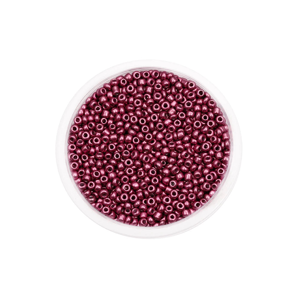 A clear container filled with small, round, deep magenta glass seed beads for jewelry making.