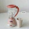 A pink and clear juicer appliance with a handle sits on a white surface.