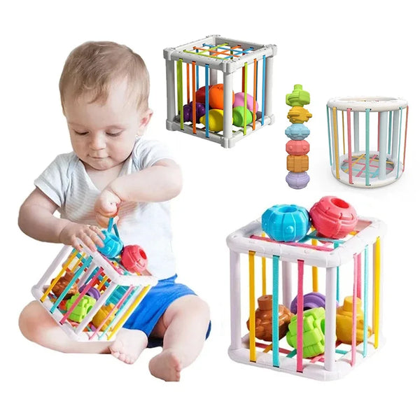 A toddler is playing with a wooden Montessori shape sorter cube featuring various colored fruit and vegetable shapes.