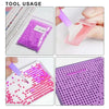 A collection of diamond painting materials including various colored and clear gems, tools, and a purple grid surface.