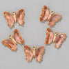 A set of delicate rose gold butterfly charm beads with pink translucent resin and clear crystal accents.