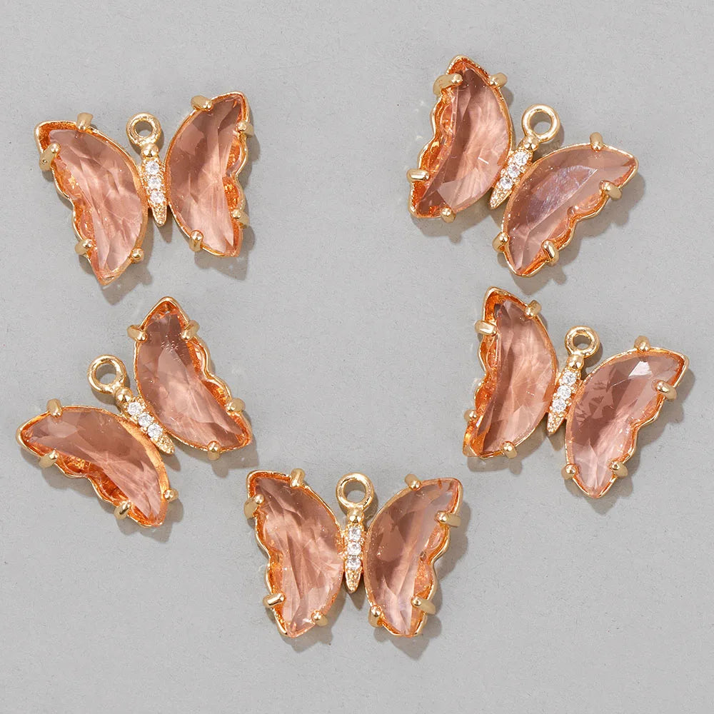 A set of delicate rose gold butterfly charm beads with pink translucent resin and clear crystal accents.