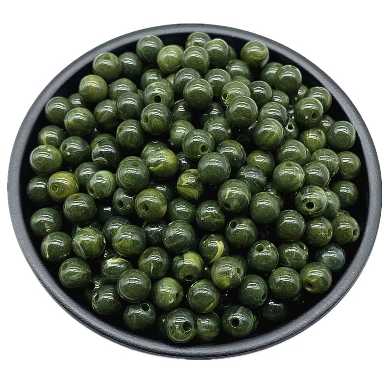 A bowl filled with small, round, olive green acrylic beads for jewelry making.