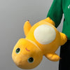 A yellow, cute dinosaur plush pillow with large eyes and a white belly is shown against a gray background.