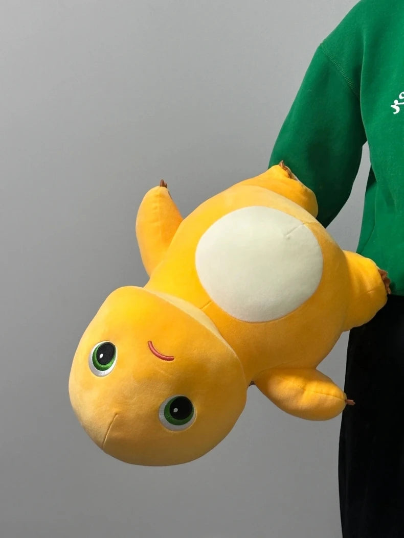 A yellow, cute dinosaur plush pillow with large eyes and a white belly is shown against a gray background.
