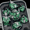 A set of black metal dice featuring a green dragon design displayed in a gray container.