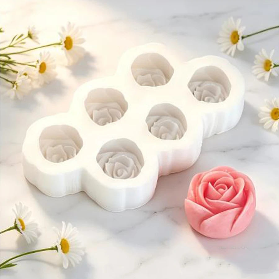 A white silicone mold set shaped like flowers is displayed on a marble surface next to a pink rose flower.
