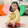 A young girl is sitting on a red balance stepping stone toy with various colored plastic stones in the background.