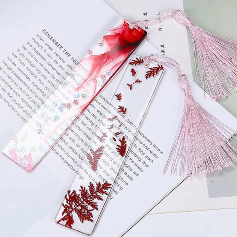 Flexible silicone molds for resin bookmarks featuring red floral designs on white paper.