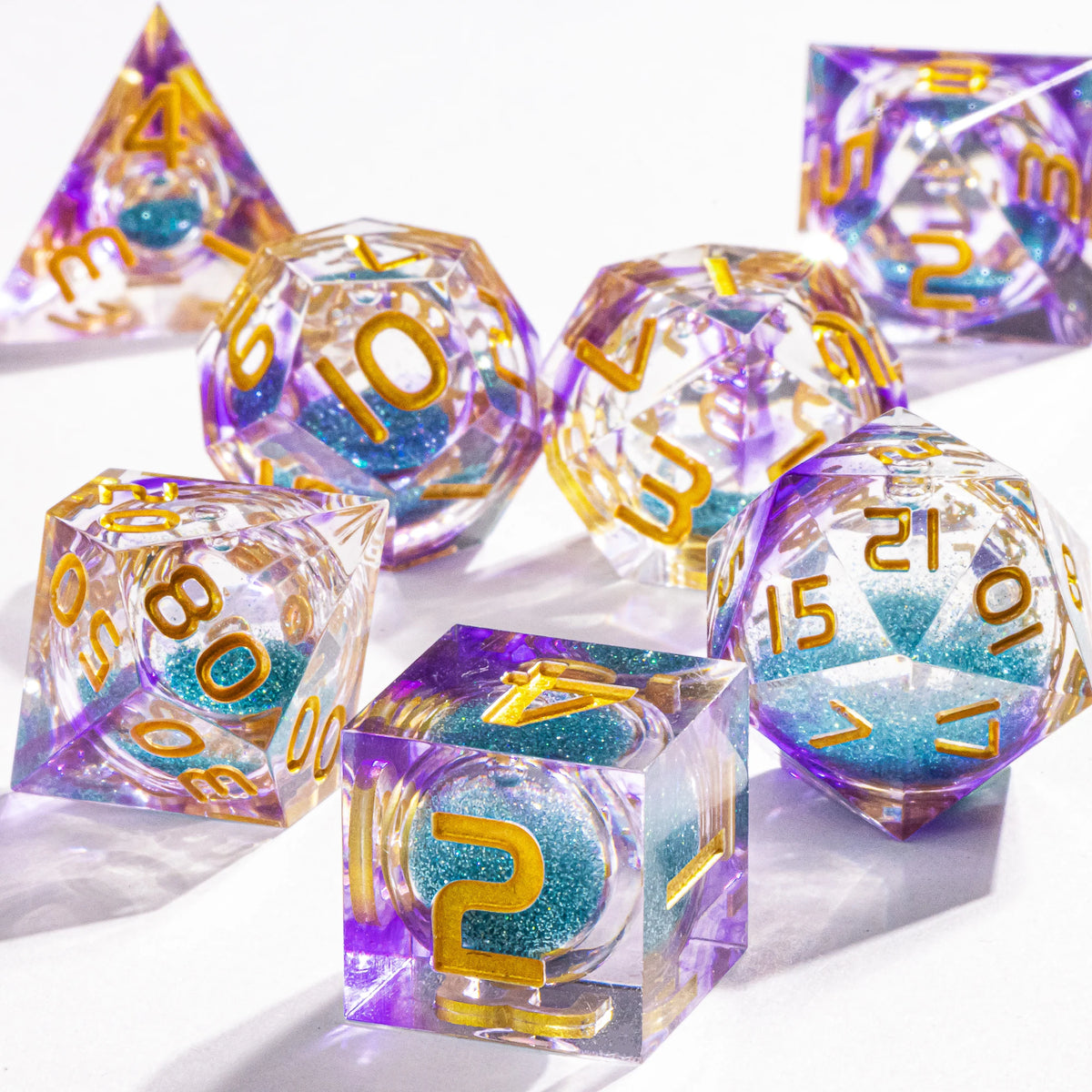 A collection of handmade liquid core polyhedral dice in purple and blue with a galaxy finish