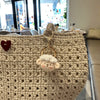A light beige handcrafted crochet animal keychain with a fluffy white rabbit charm hanging on a textured bag.