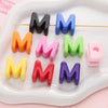 A collection of colorful acrylic letter beads in various shades of black, blue, orange, pink, green, and purple arranged on a