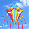 A colorful diamond-shaped kite with a rainbow design is shown flying against a blue sky.