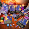 A collection of Akashic Oracle cards and a deck box displayed on a wooden surface with various crystals.