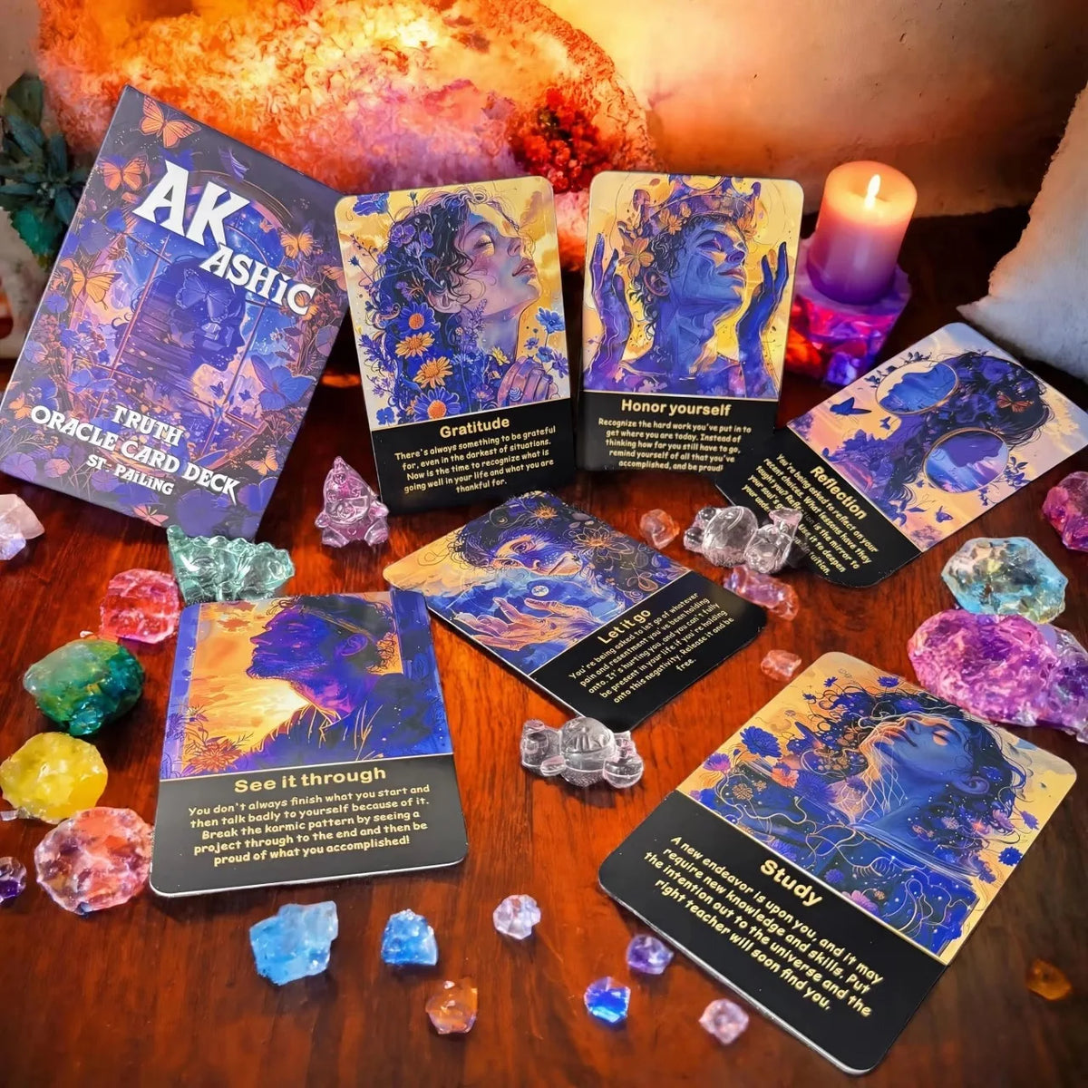 A collection of Akashic Oracle cards and a deck box displayed on a wooden surface with various crystals.