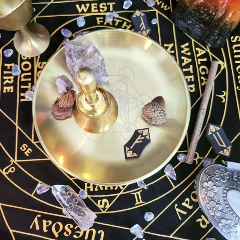 A brass pentagram altar plate holds crystals, parchment, and natural elements on a dark background.
