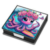 A vibrant illustration of a pink octopus with floral tentacles and butterfly accents on a black box.