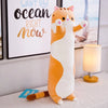 An orange and white plush cat toy standing upright in front of a sign that reads Want the ocean right now