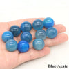 A hand holds several smooth, round blue agate crystal spheres of varying shades and sizes.