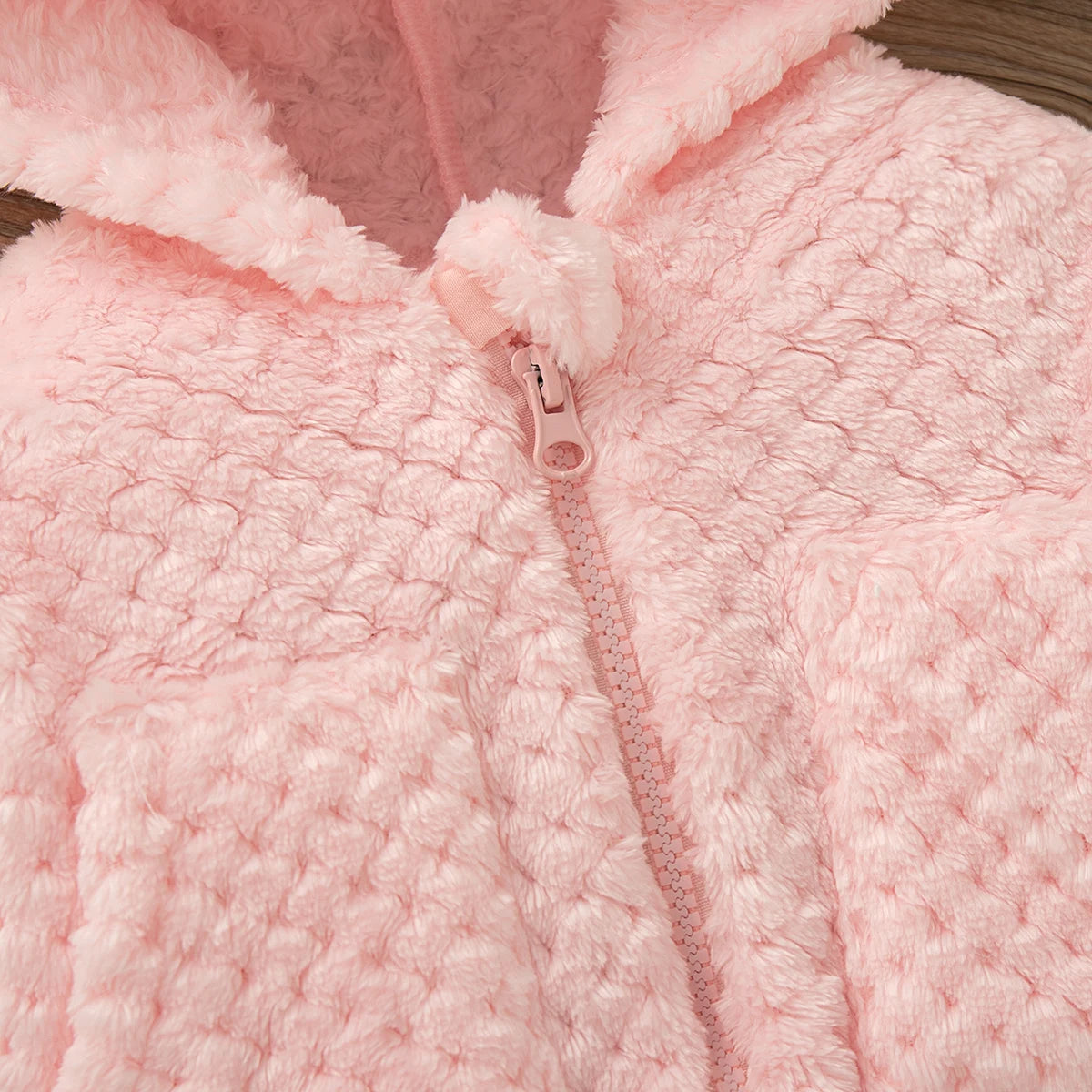 Close-up of a pink plush hooded winter jacket with a zipper closure