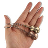 A pair of vintage gold-toned violin keychains hanging from silver chains held in a person's hand.
