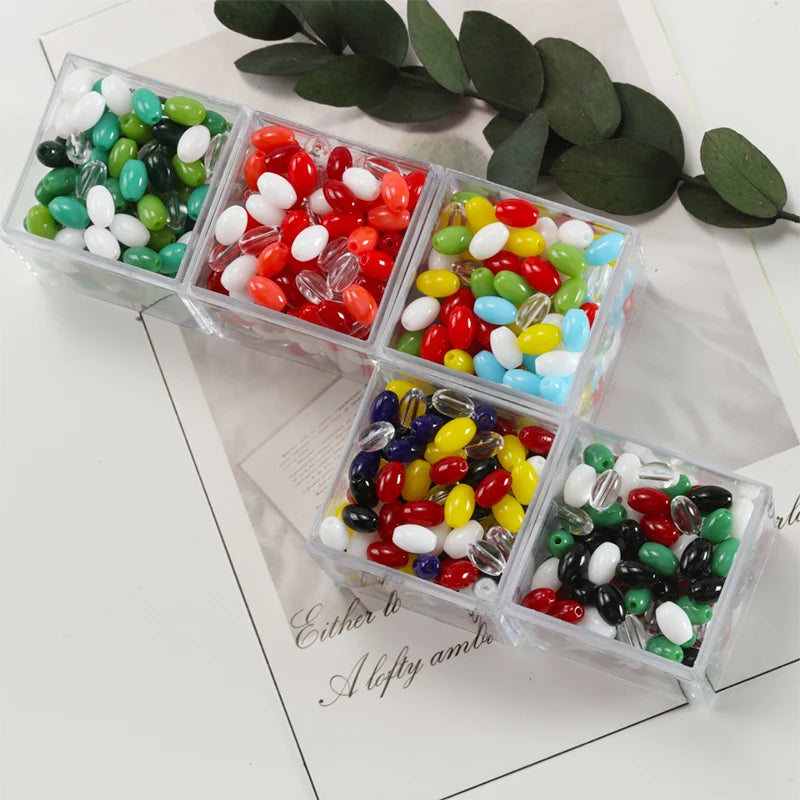 Assortment of oval glass rice grain beads in various colors like green, red, white, and yellow, packaged in clear containers.