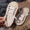 A pair of wooden lacing shoes toy with white laces resting on a woven mat.