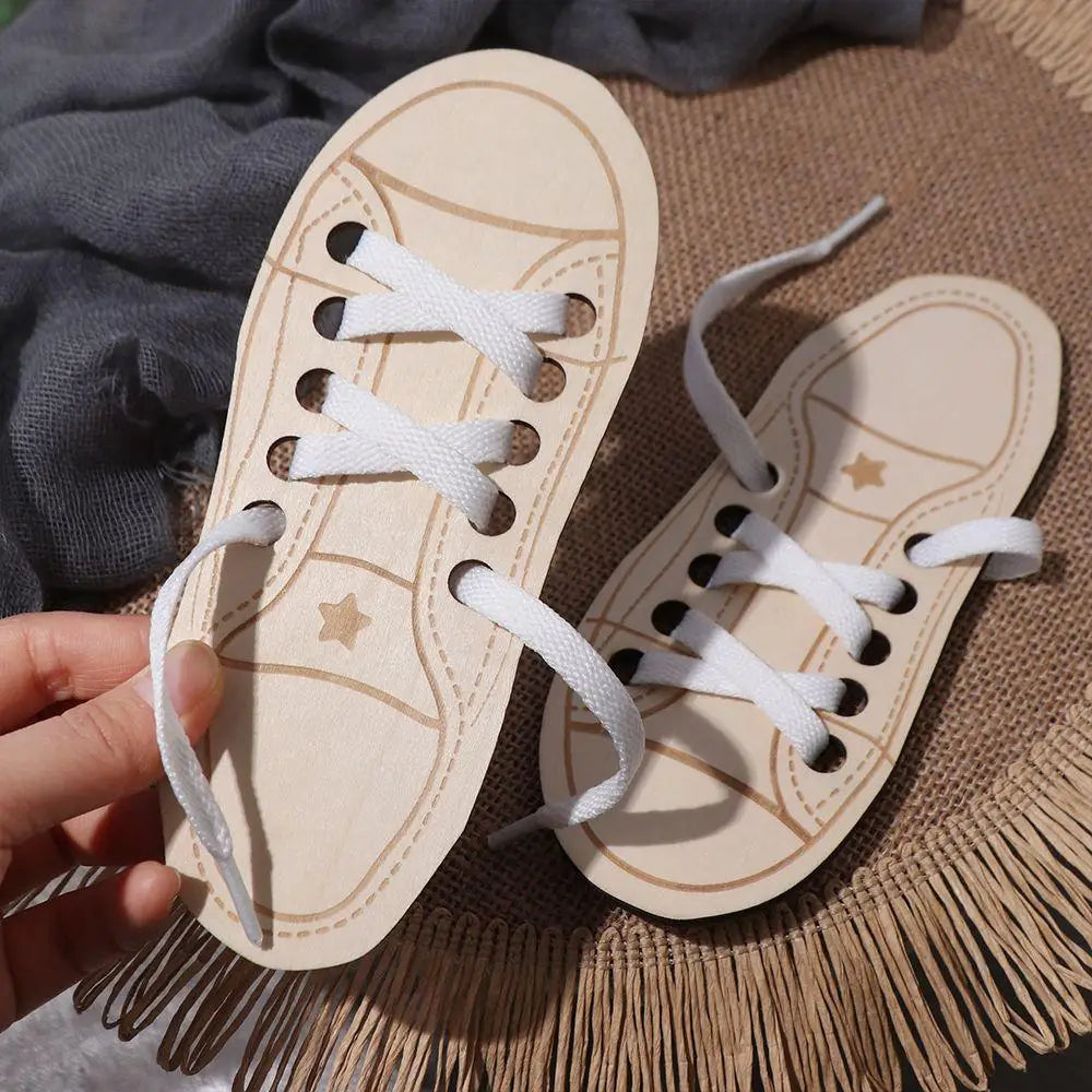 A pair of wooden lacing shoes toy with white laces resting on a woven mat.