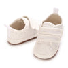 A pair of classic white soft-sole baby first walkers with padded soles and elasticized straps.