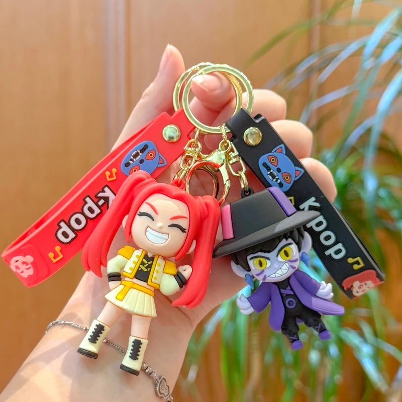 A hand holds a Kpop Rumi keychain charm featuring an anime-style character with red hair and purple clothing.